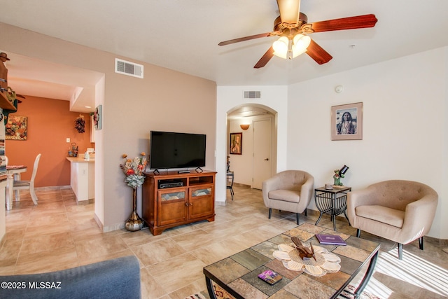 living room with baseboards, visible vents, arched walkways, and ceiling fan