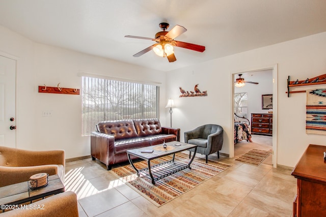 living area with light tile patterned flooring, baseboards, and a ceiling fan