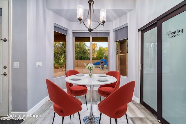 dining area featuring light wood finished floors, baseboards, and a chandelier