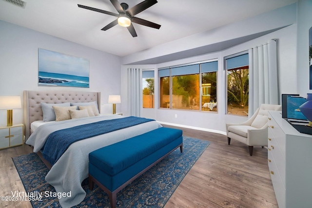 bedroom featuring visible vents, baseboards, wood finished floors, and ceiling fan