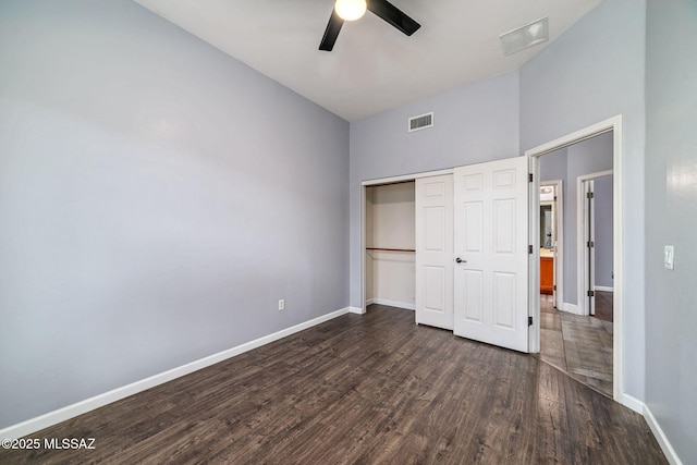 unfurnished bedroom with visible vents, baseboards, dark wood-style floors, and a closet