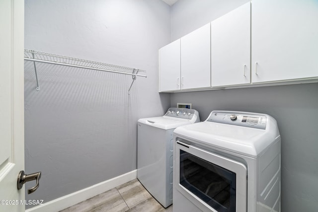 laundry area featuring cabinet space, baseboards, and separate washer and dryer