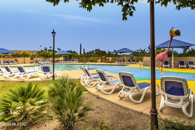 community pool with a patio area and fence