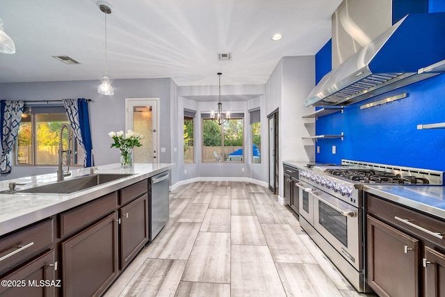kitchen featuring visible vents, a sink, appliances with stainless steel finishes, and wall chimney range hood