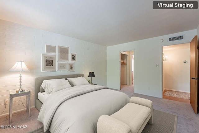 bedroom featuring a spacious closet, light carpet, baseboards, and visible vents