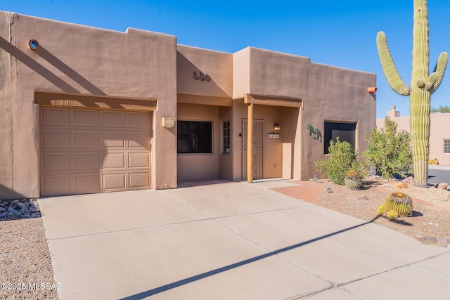 pueblo-style home with concrete driveway and stucco siding