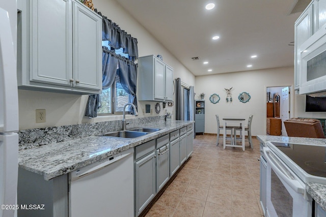 kitchen with white appliances, recessed lighting, a sink, gray cabinets, and light tile patterned floors