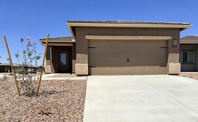 prairie-style house with a tiled roof, driveway, and stucco siding