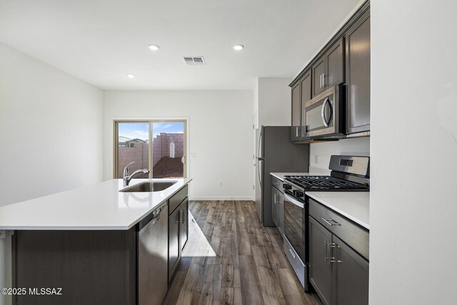 kitchen featuring dark brown cabinetry, visible vents, appliances with stainless steel finishes, a sink, and light wood-style flooring