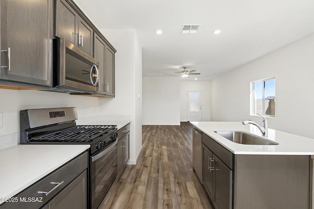 kitchen featuring visible vents, wood finished floors, light countertops, a sink, and appliances with stainless steel finishes