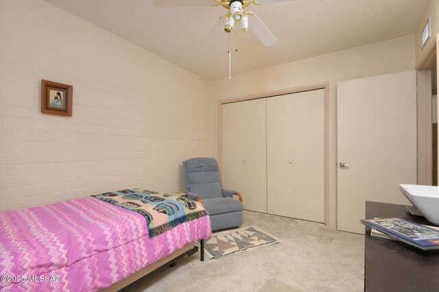 carpeted bedroom with visible vents, a closet, ceiling fan, and brick wall