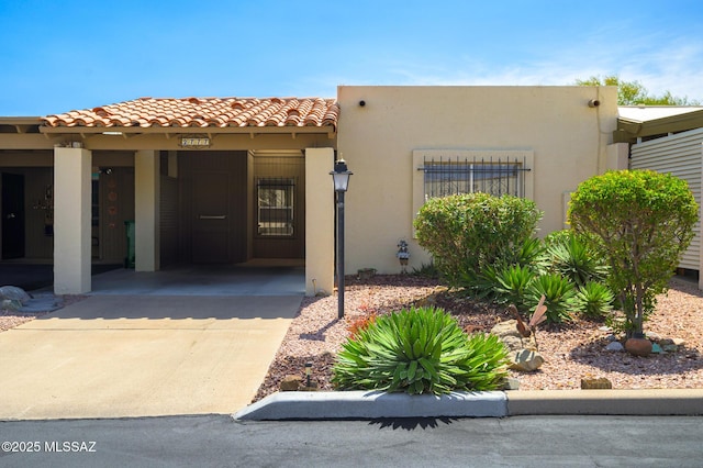 view of front facade featuring a tiled roof, an attached carport, driveway, and stucco siding