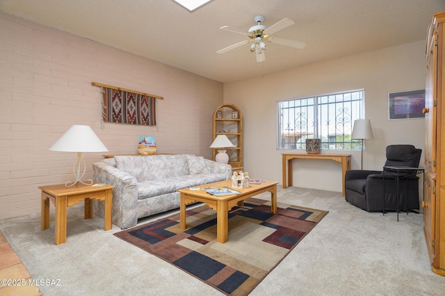 living area with light colored carpet, ceiling fan, and brick wall