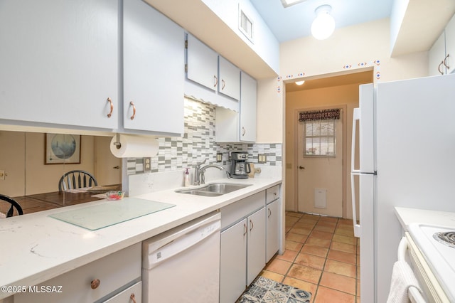 kitchen with light countertops, a sink, tasteful backsplash, and white appliances