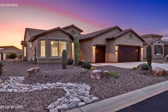 view of front of property featuring fence, stucco siding, a tiled roof, an attached garage, and driveway