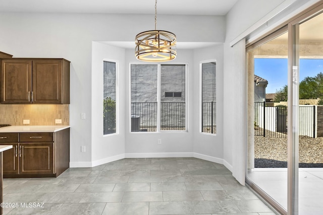 unfurnished dining area with baseboards and a notable chandelier