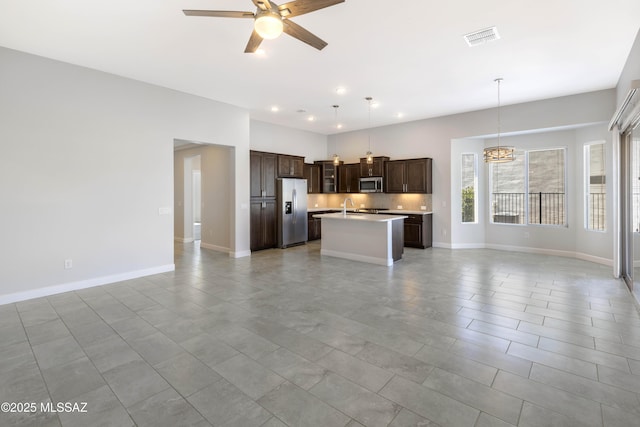 kitchen featuring dark brown cabinets, appliances with stainless steel finishes, light countertops, open floor plan, and visible vents