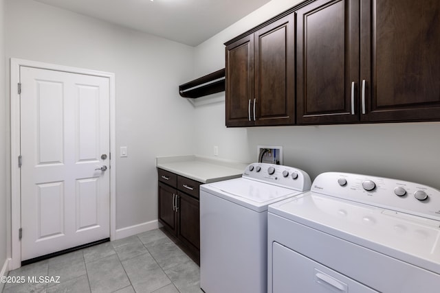 clothes washing area with cabinet space, baseboards, and washer and clothes dryer