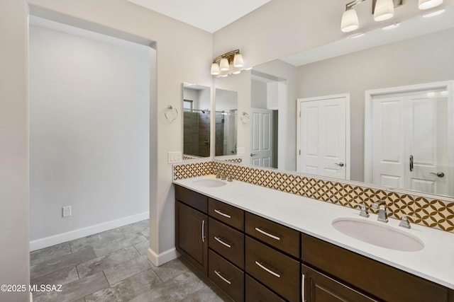 bathroom with double vanity, baseboards, a sink, and a stall shower
