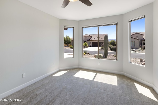 unfurnished room with baseboards, ceiling fan, a wealth of natural light, and carpet