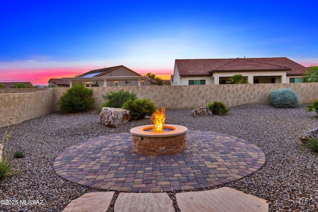 patio terrace at dusk with a fenced backyard and a fire pit