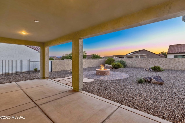patio terrace at dusk featuring a fenced backyard and a fire pit