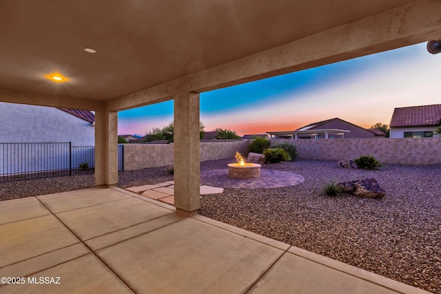 patio terrace at dusk with a fenced backyard and an outdoor fire pit