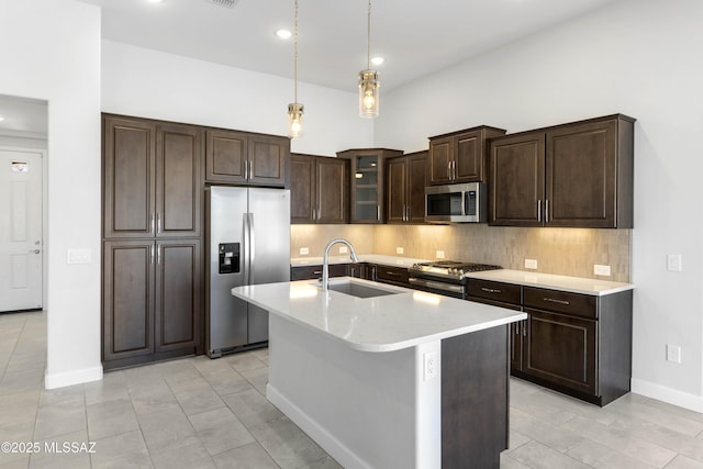 kitchen featuring dark brown cabinetry, tasteful backsplash, a sink, appliances with stainless steel finishes, and decorative light fixtures