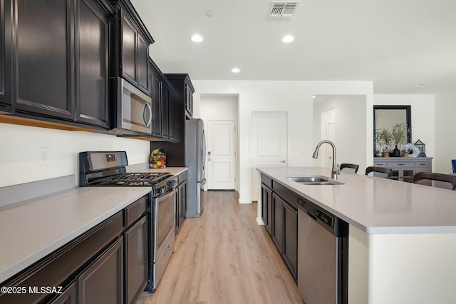14239 E Axle Dr, Vail, AZ 85641 - kitchen featuring stainless steel appliances, a sink, light wood-style flooring, a kitchen island with sink, and dark cabinetry
