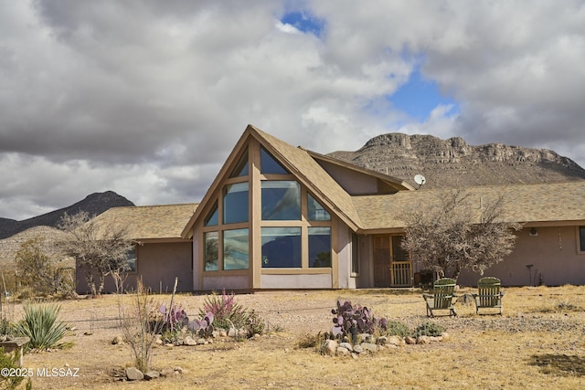 rear view of property with stucco siding and a mountain view