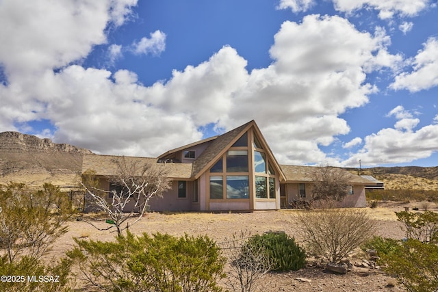 back of house with stucco siding and a mountain view