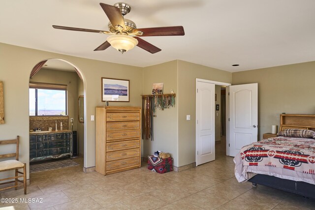 bedroom with arched walkways, ceiling fan, baseboards, and light tile patterned flooring