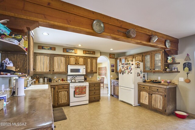 kitchen with white appliances, arched walkways, a sink, open shelves, and brown cabinetry