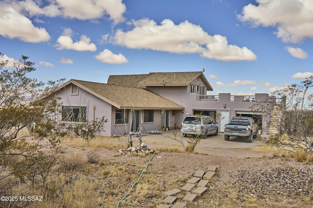 rear view of house with stucco siding and concrete driveway
