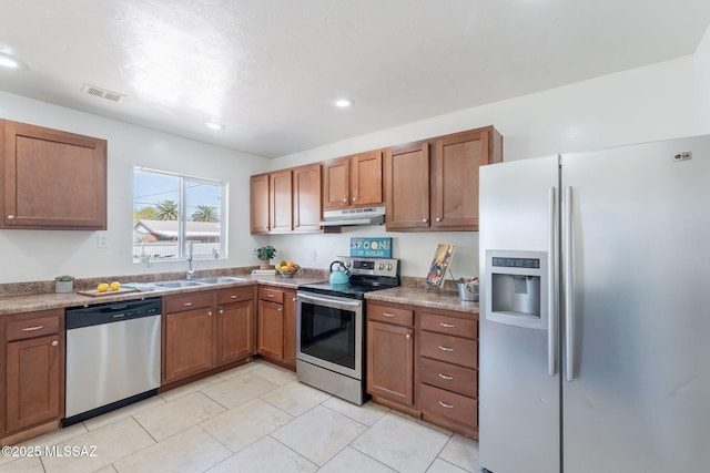 6517 E Cooper St, Tucson, AZ 85710 - kitchen featuring appliances with stainless steel finishes, a sink, under cabinet range hood, brown cabinets, and light tile patterned floors