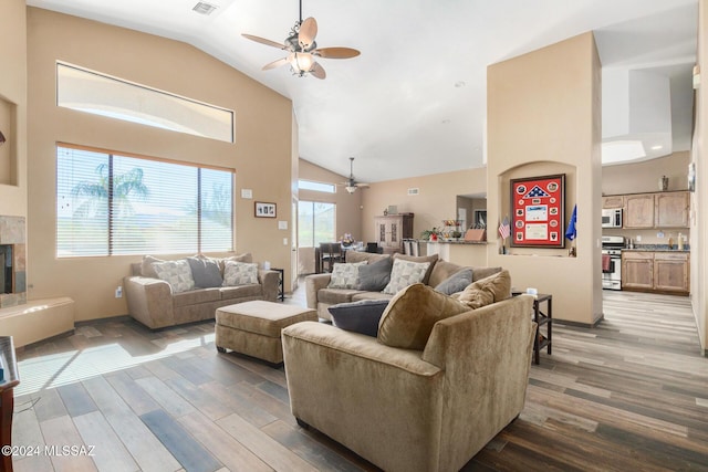 living area with high vaulted ceiling, ceiling fan, wood finished floors, and a tile fireplace