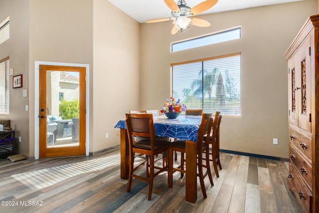 dining area with wood finished floors, a towering ceiling, and a ceiling fan