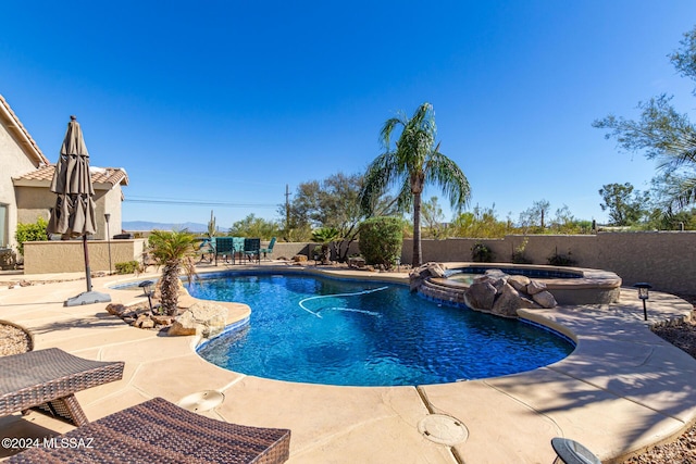 view of pool with a fenced backyard, a pool with connected hot tub, and a patio area