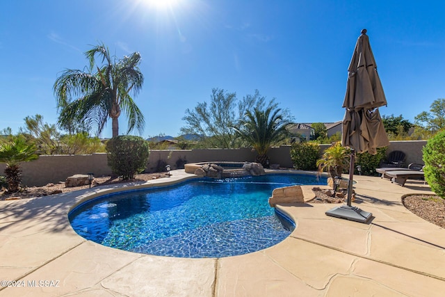 view of pool featuring a fenced backyard, a pool with connected hot tub, and a patio area