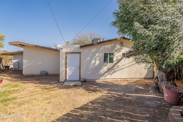 rear view of house with central AC unit and stucco siding