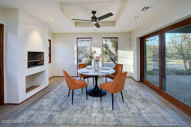 dining space featuring recessed lighting, wood finished floors, ceiling fan, visible vents, and a raised ceiling