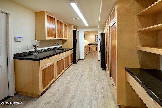 kitchen featuring refrigerator, visible vents, a sink, and light wood-type flooring