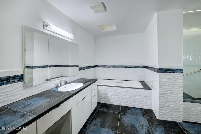 full bathroom featuring tile walls, wainscoting, a garden tub, and vanity