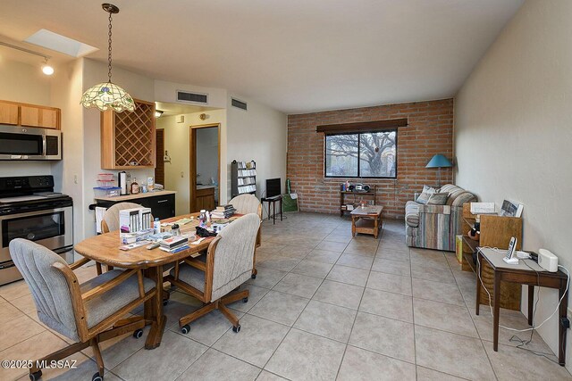 dining space featuring light tile patterned flooring, visible vents, and brick wall