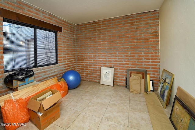 workout area featuring light tile patterned flooring and brick wall