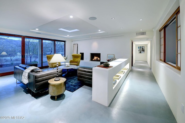 living area featuring visible vents, a raised ceiling, finished concrete flooring, and recessed lighting