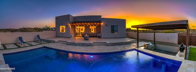pool at dusk featuring exterior kitchen, a patio, fence, and a fenced in pool