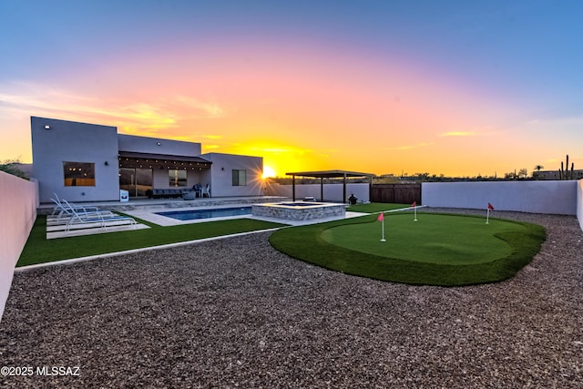 back of property at dusk with a patio, a fenced backyard, stucco siding, and a pool with connected hot tub