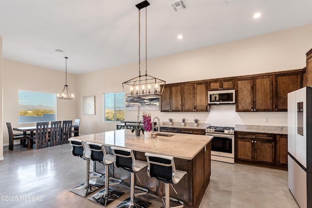 kitchen featuring stainless steel gas stove, freestanding refrigerator, finished concrete floors, visible vents, and a sink