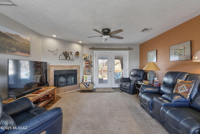 living room featuring carpet flooring, french doors, a fireplace, visible vents, and ceiling fan